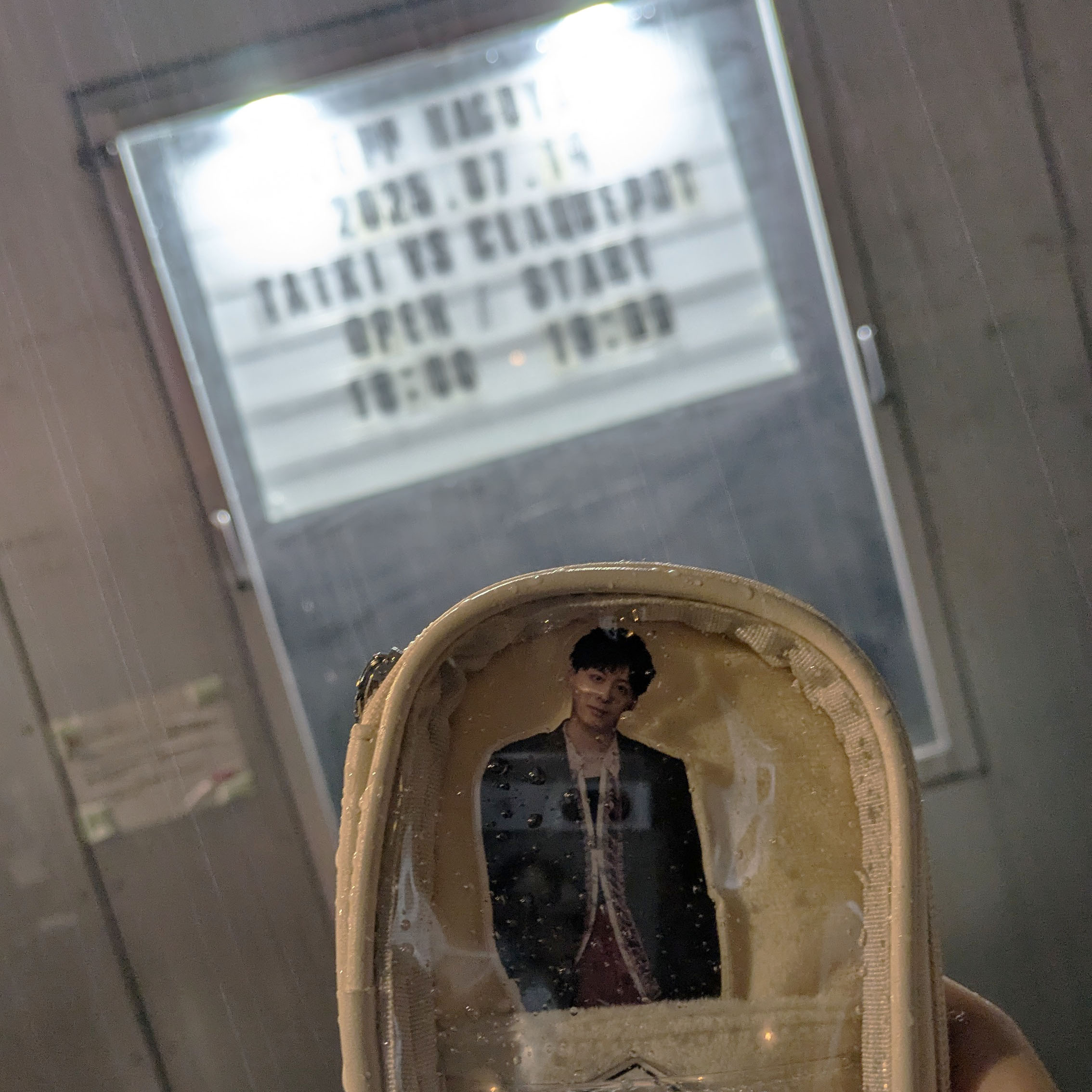 出演者看板前でアクリルスタンドを持った写真